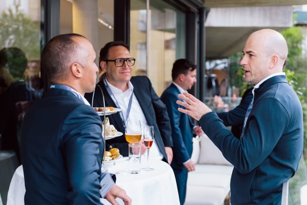 Gäste im Gespräch an einem Tisch mit Fingerfood und Getränken