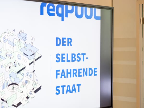 Bildschirm mit der Titelfolie „Der selbstfahrende Staat“ und der Illustration einer digitalen Stadt