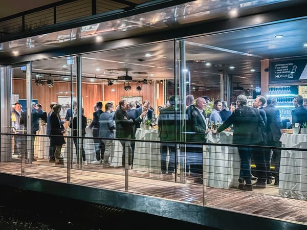 Blick von außen durch die Glasfront auf den abendlich beleuchteten Veranstaltungsraum