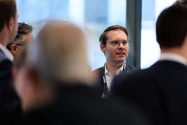 Gast im Gespräch, im Vordergrund unscharfe Rücken anderer Gäste