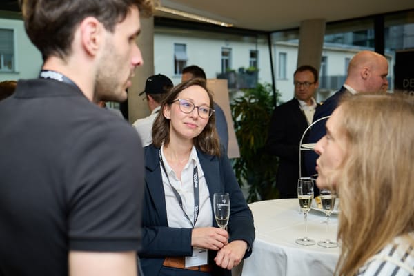 Gästin mit Sektglas im Gespräch an einem Stehtisch