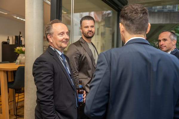 Gäste mit Bier im Gespräch vor der Fensterfront