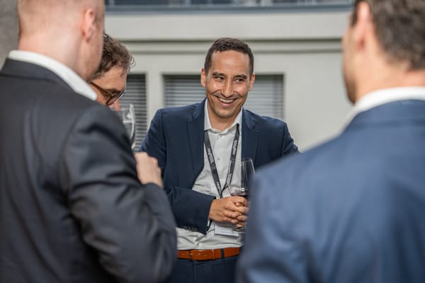 Lachender Gast mit Getränk im Gespräch mit anderen Gästen