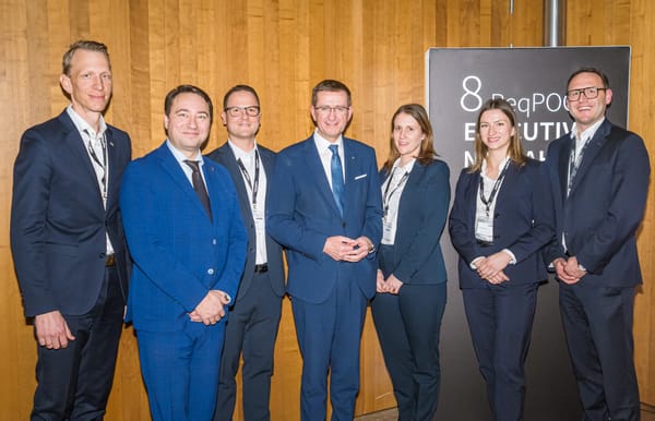 Sieben Personen posieren vor einer Tafel zum 8. ReqPOOL Executive Neujahrscocktail