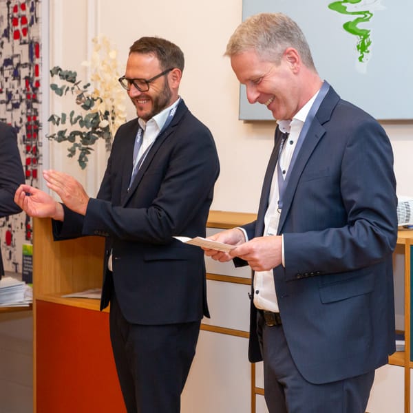 Zwei Gäste lachen über ein Blatt Papier am Empfangstresen